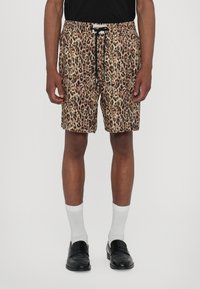 Luipaardprint shorts met een elastische tailleband, aantrekkoord en zijzakken, gemaakt van lichtgewicht stof, gecombineerd met zwarte instappers en witte sokken.