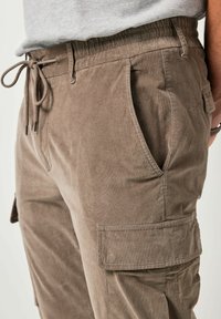 Bruine corduroy cargo shorts met een elastische tailleband en trekkoord, voorzien van zijzakken en een klepzak op de dij.
