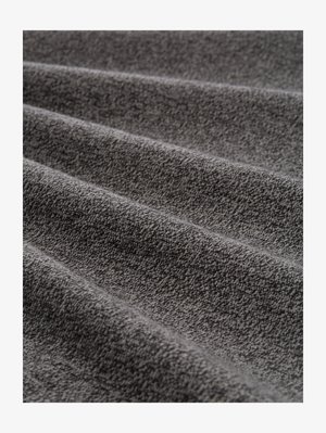 Tessuto grigio strutturato con finitura morbida, caratterizzato da un motivo sottile e pieghe ondulate, che illustrano profondità e dimensione.