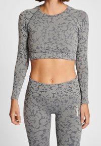 Top corto de manga larga gris y leggins de cintura alta a juego con un sutil patrón abstracto. Textura acanalada, diseño atlético, estilo ajustado.