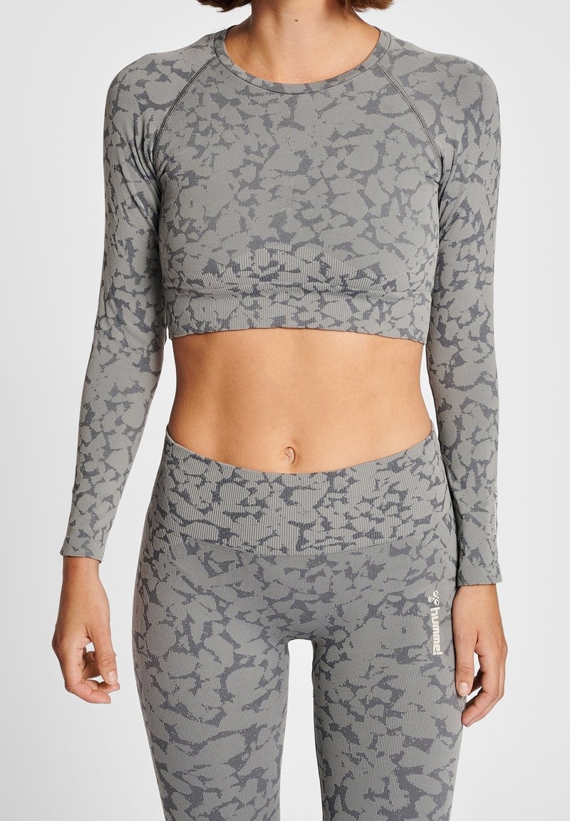 Top corto de manga larga gris y leggins de cintura alta a juego con un sutil patrón abstracto. Textura acanalada, diseño atlético, estilo ajustado.