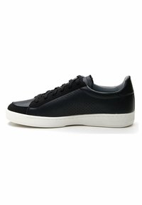 Black leather sneaker with perforated side detailing, textured toe cap, and white rubber sole. Features black laces and a low-cut design.