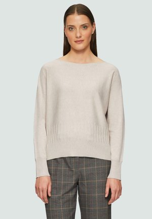 Maglione a maglia beige chiaro con scollatura ampia, polsini a coste e una texture sottile. Abbinato a pantaloni a quadri grigi a vita alta.