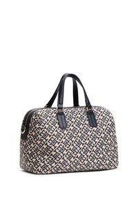 Borsa beige e blu navy con motivo geometrico, manici in pelle, chiusura con zip e dettagli in metallo dorato. La superficie in tessuto ha una finitura testurizzata.