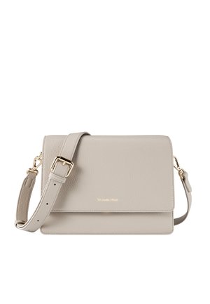 Sac en cuir synthétique gris clair avec finition texturée, quincaillerie dorée, sangle réglable et fermeture rabat. Présente un logo en relief.