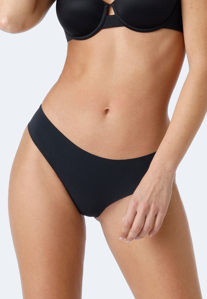 Perizoma nero con una texture di tessuto liscia, design a vita bassa e copertura minima. Presenta una cintura pulita e senza cuciture.
