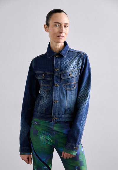 Chaqueta de mezclilla con textura acolchada en un lado, de color azul oscuro con acentos en azul más claro en contraste, que cuenta con bolsillos frontales y cierre de botones.