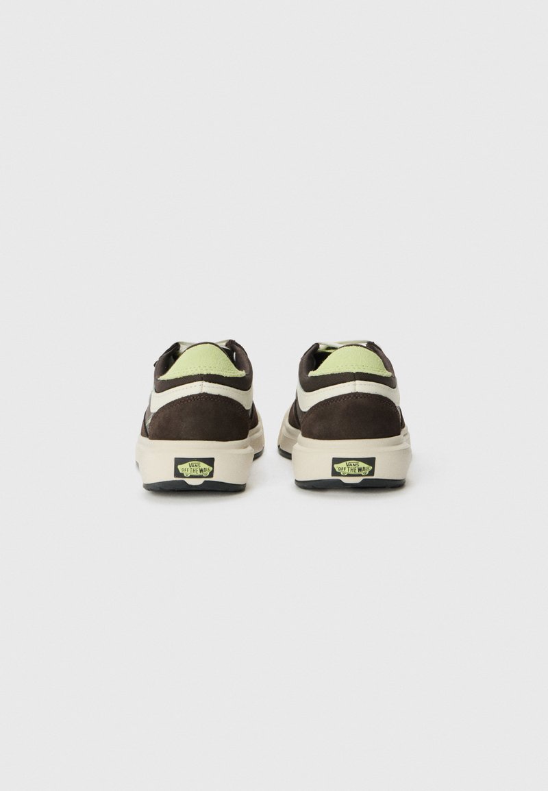 Zapatillas de ante marrón con una entresuela crema, detalles verdes en el talón y una suela de goma negra que presenta el logotipo de la marca.