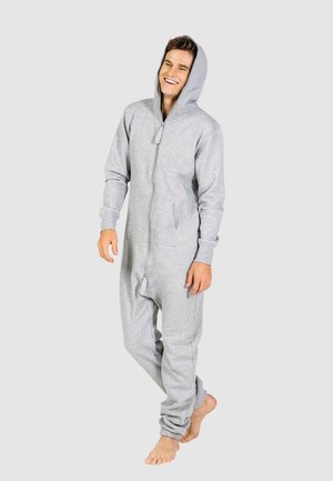 Gray fleece onesie with a full zipper, hood, and front pockets. Cuffs are slightly elasticated. Model stands barefoot against a neutral background.