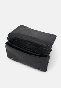 Černá kožená taška s klopou, dvěma zacvakávacími knoflíky a několika vnitřními přihrádkami pro organizaci. Měkká textura s minimálními detaily.