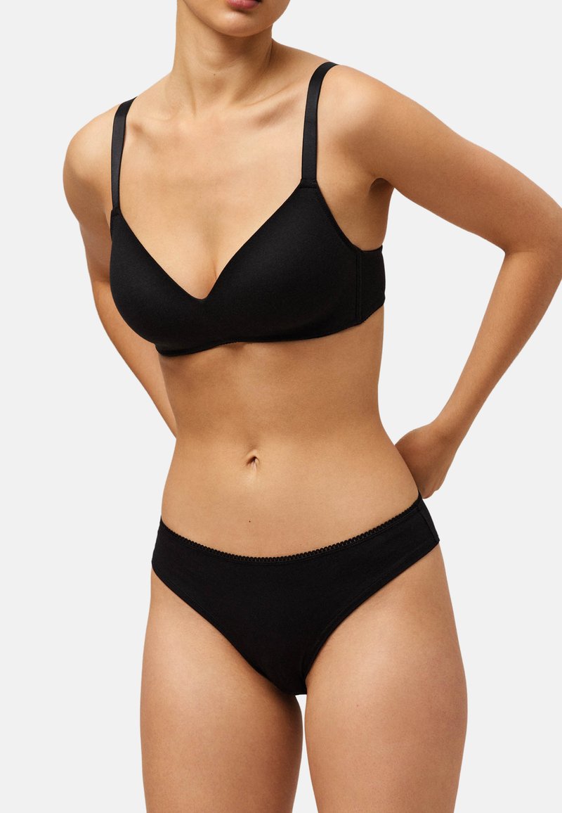 Sujetador inalámbrico negro con una tela suave y texturizada y un escote en V profundo, combinado con braguitas estilo bikini negras a juego con un delicado borde.