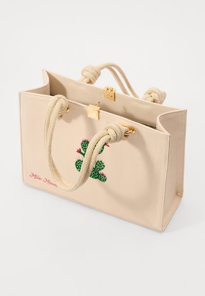Beige canvas tote bag with rope handles, featuring a cactus embroidery design and a gold clasp detail. Accented with "Mile Mountain" text.