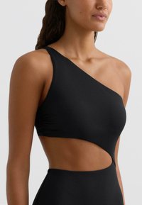 Čierne jednodielne plavky s jedným ramienkom, ktoré sa vyznačujú elegantným dizajnom s výrezom na boku, vyrobené z hladkého, pružného materiálu.