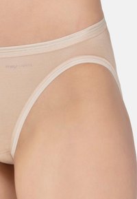 Lähikuva beigeistä puuvillapikkareista, joissa on elastinen vyötärö ja lahkeet.