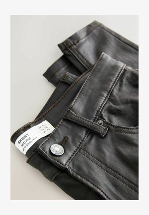 Dünne, hoch geschnittene Jeans aus dunkelgrauem Stoff. Merkmale sind Ziernähte, ein Metallknopf und ein Etikett mit Größen- und Pflegehinweisen.