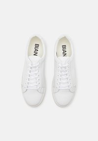 Baskets en cuir blanc à bouts ronds, surface texturée, lacets plats et design minimaliste. Nom de la marque "BIAN" imprimé sur les semelles intérieures.