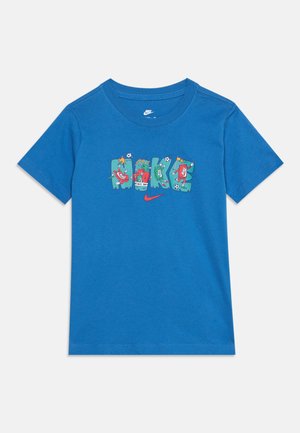T-shirt Nike bleu à manches courtes avec des lettres colorées en blocs formant "NIKE" et des graphiques sur le thème du football, ainsi qu'un petit swoosh Nike rouge en dessous.