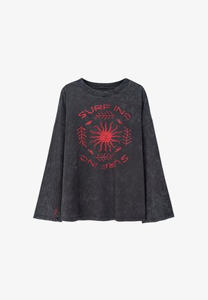 Czarna koszulka z długim rękawem o luźnym kroju. Posiada czerwoną grafikę przedstawiającą słońce i napis „SURF INC” otoczony liśćmi. Miękka w dotyku.