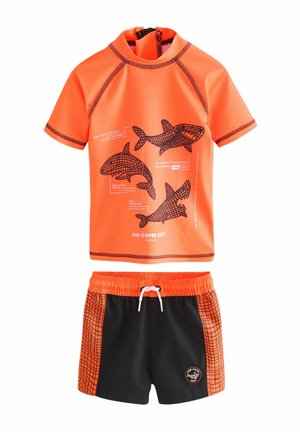 Ljust orange kortärmad rash guard med hajgrafik; svarta simshorts med orange rutmönster. Elastisk midja med dragsko.