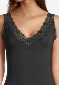 Black sleeveless top featuring a V-neckline trimmed with intricate black lace. Soft, stretch fabric with a smooth texture.