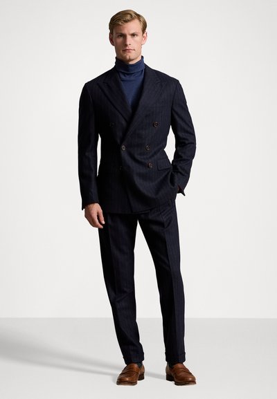 Divraka jūras zila pinstripe uzvalks ar dubultām pogām un pielāgotu piegriezumu, saskaņots ar jūras zilu turtleneck un brūniem ādas apaviem. Gluda tekstūra un strukturēts dizains.