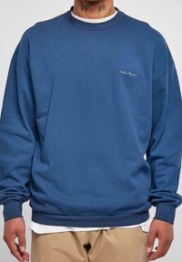 Felpa blu a girocollo realizzata in cotone, caratterizzata da una vestibilità comoda, polsini a coste e un piccolo logo ricamato sul petto.