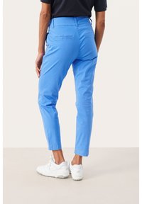 Light blue trousers with a straight cut, belt loops, and back pockets, paired with white athletic shoes. Smooth fabric and tailored fit.