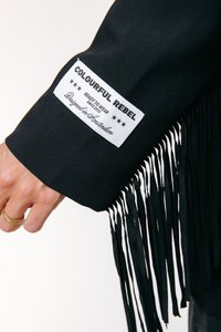 Fekete dzseki, csipkés részletekkel az ujjon. Fehér márkajelzés található rajta, amelyen az "COLOURFUL REBEL" felirat olvasható.
