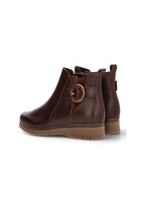 Botas de tobillo de cuero marrón con puntera redondeada, cremallera lateral y un acento circular en el tacón. Parte superior texturizada y suela de goma.