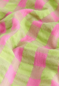 Tissu à carreaux rose et vert citron avec un tissage doux et texturé, présenté avec des plis légers créant des ombres et des reflets.