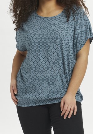 Blauwe top met een patroon, losse fit, korte mouwen en een ronde halslijn met een onderling verbonden ovaal ontwerp. Gecombineerd met zwarte onderkleding.