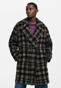 Double-breasted plaid coat featuring black, beige, and multicolor threads. Made from textured fabric with large notched collar and side pockets.