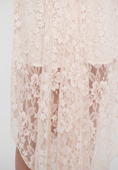 Material dantelă în nuanță moale de roz, cu modele florale și textură semi-transparentă, aranjat elegant cu un strat interior parțial vizibil.
