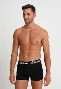 Cuecas boxer pretas com cintura elástica branca apresentando o logótipo "ellesse". Tecido macio, design ajustado e comprimento até meio da coxa.