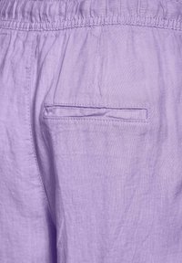 Levandulové lněné šortky s elastickým pasem a zadní kapsou se plochým, šitým švem. Měkká textura s jemným leskem.