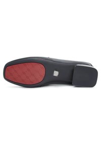 Semelle de chaussure plate noire avec une prise texturée rouge à l'avant et un autocollant de taille 39 près de la voûte plantaire sur un fond blanc.