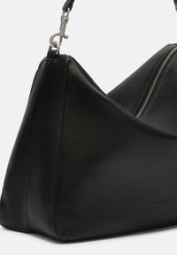 Sac en cuir noir de forme triangulaire, doté d'une fermeture éclair et d'accents en métal argenté. Texture lisse avec des coutures visibles.