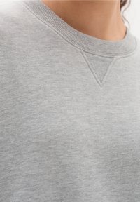 Helles graues Sweatshirt mit runder Halslinie, gerippten Bündchen und einem strukturierten Stoffmix, der ein einfaches, lässiges Design zeigt.