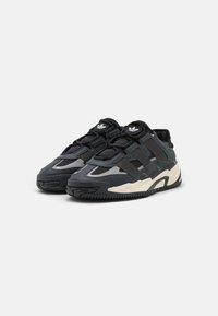 Czarno-szare sportowe sneakersy z siateczkową cholewką, gumową podeszwą, designem w trzy paski oraz teksturowaną podeszwą. Klasyczne akcenty logo.