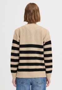 Sweter w beżowo-czarną poziomą paski z prążkowanymi mankietami i dołem. Dzianinowa tkanina ma teksturowany wygląd, z szerokimi poziomymi paskami.