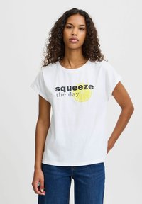 Valge lühikeste varrukatega T-särk, millel on "squeeze the day" tekst ja kollane laimi graafika. Valmistatud pehmest puuvillast. Üksikasjalik ja ümar kaelus.