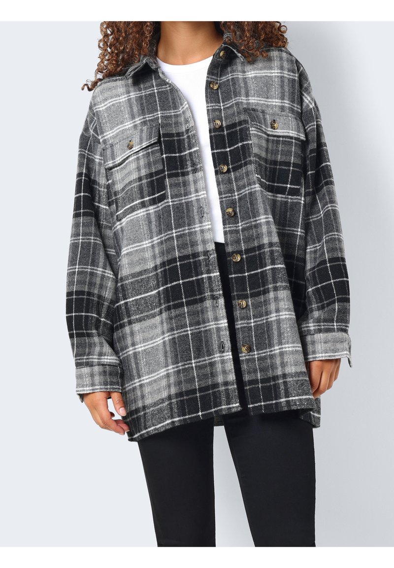 Czarna i szara flanelowa koszula w kratę z dwoma kieszeniami na piersi i złotymi guzikami, o luźnym kroju i długich rękawach. Miękka tekstura.