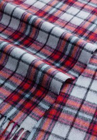 Soft woolen fabric with a red, pink, and gray plaid pattern, folded and showing fringed edges.