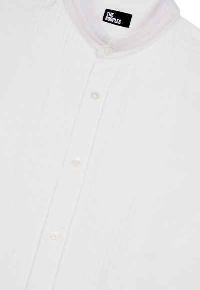 Witte shirt met een opstaande kraag, voorzien van verticale streepjes, sluiting met knopen aan de voorkant en een subtiele glans. Label: The Kooples.