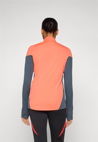 Fitted long-sleeve top in coral and navy blue, featuring a high collar, contrasting sleeves, and smooth texture suitable for active wear.