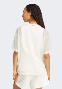 Witte korte mouwen shirt met doorschijnende stofpanelen, ronde halslijn, opgerolde mouwen en een ontspannen pasvorm, gecombineerd met bijpassende shorts.