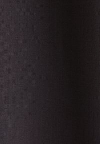 Tessuto intrecciato scuro con una trama compatta ed uniforme, illuminato da luci sottili che mettono in evidenza il disegno delle fibre.