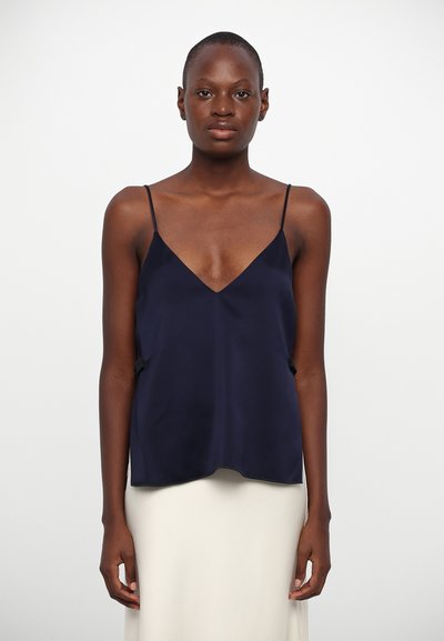 Camisole en satin marine avec des bretelles spaghetti, présentant un décolleté en V et une coupe fluide. Texture lisse et style minimaliste.
