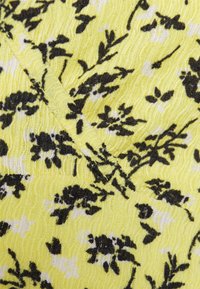 Tecido de vestido floral com um fundo amarelo e padrões de flores em preto e branco, superfície texturizada e um discreto design em ondas.