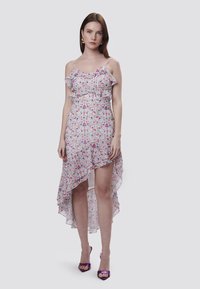 Vestido con estampado floral, con tirantes con volantes, cintura entallada y dobladillo asimétrico, fabricado con una tela ligera en tonos de rosa y azul.